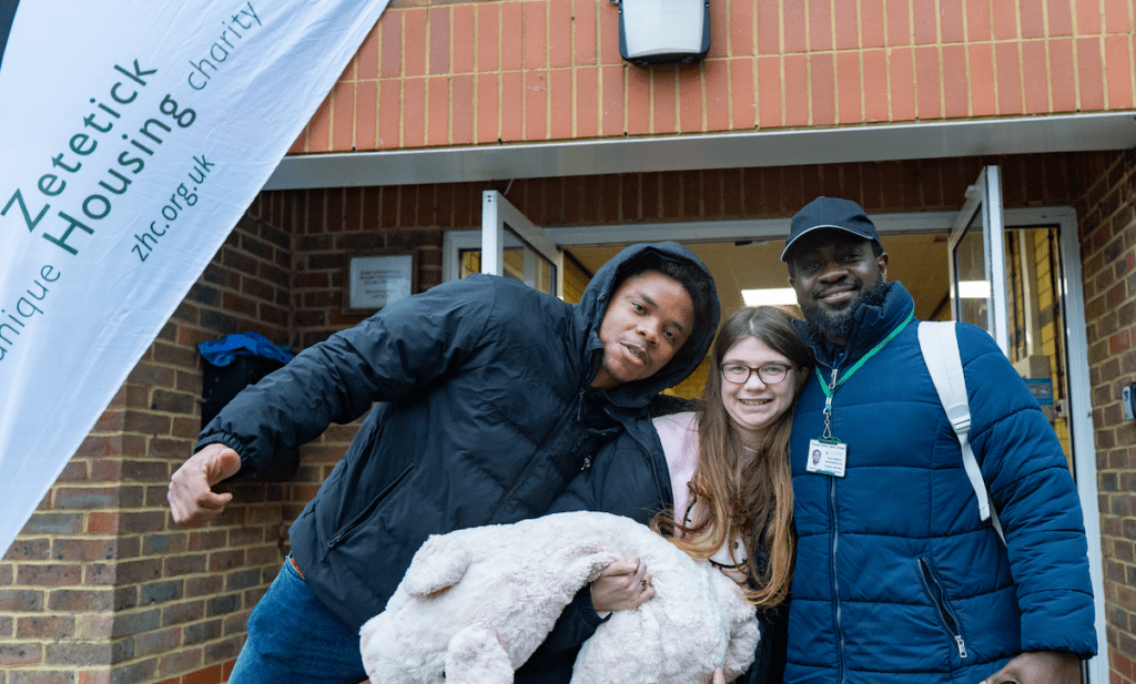 Three people smiling outside Zetetick Housing charity.