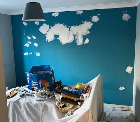 Room interior, blue wall, plaster patches, renovation tools.