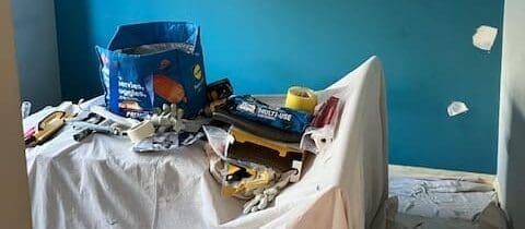 Room interior, blue wall, plaster patches, renovation tools.